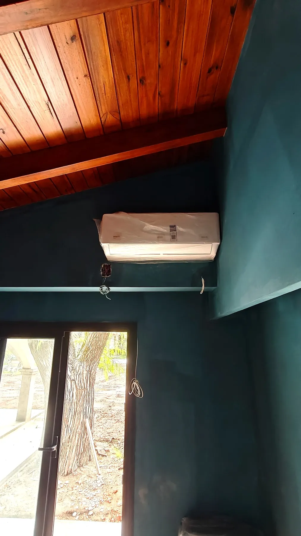 Split nuevo instalado en una pared verde con techo de madera