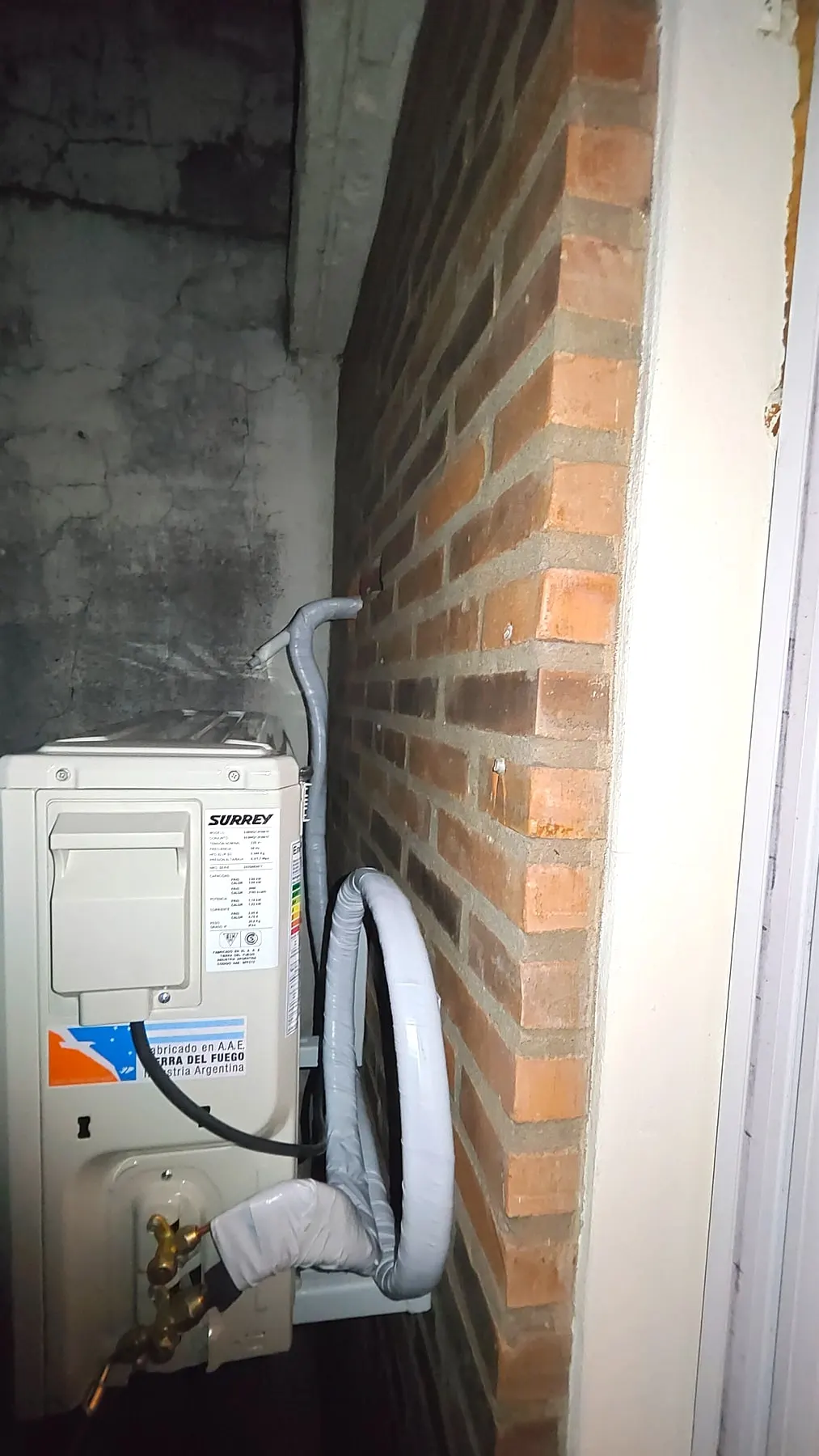 Unidad exterior instalada en una pared de ladrillo