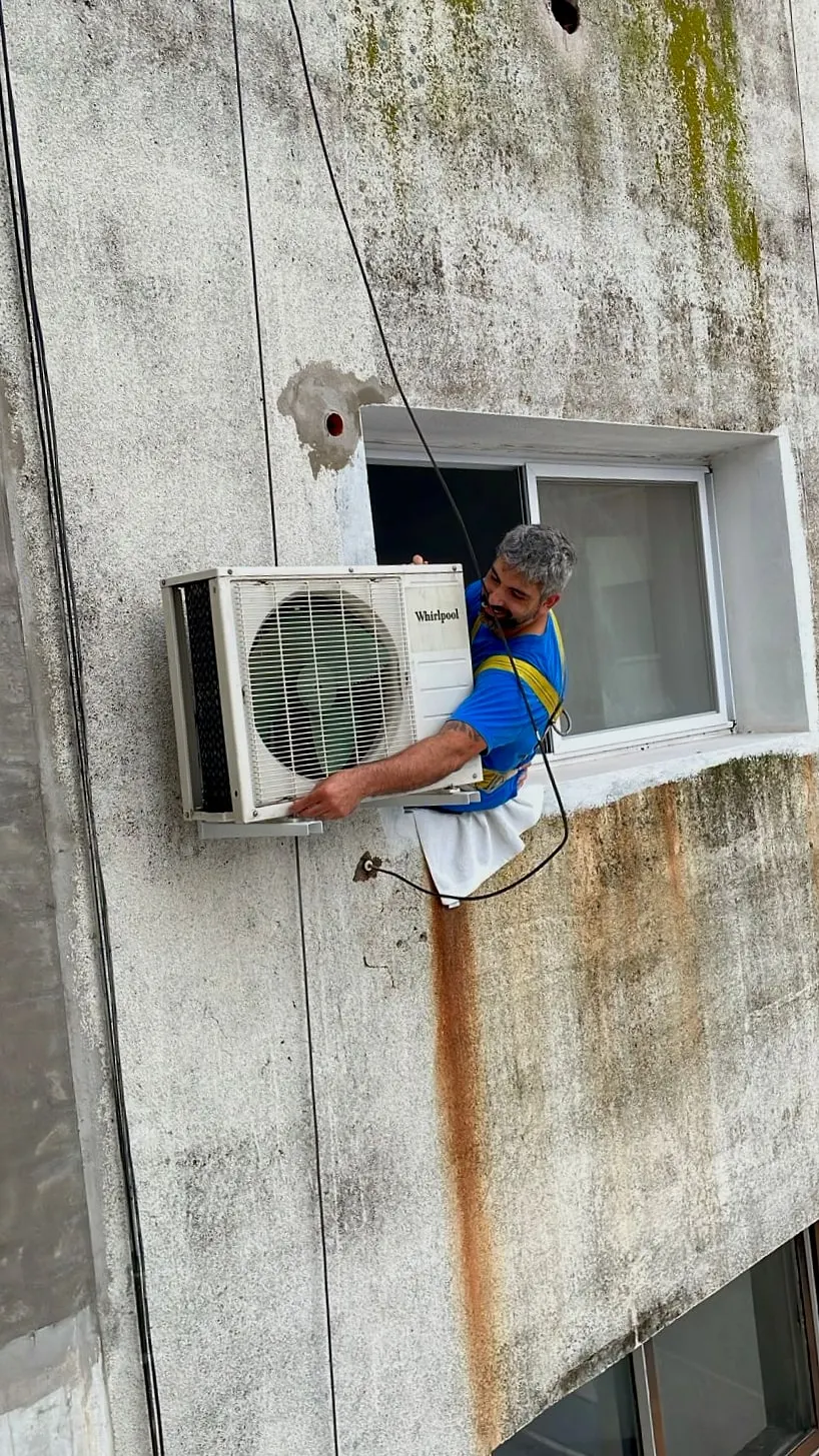 Técnico montando la unidad exterior desde la ventana